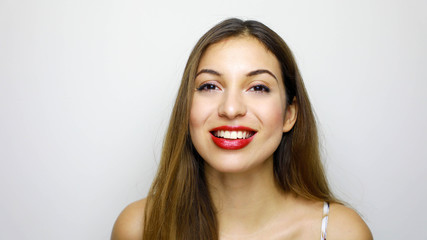 Portrait of young beautiful shy girl smiling looking at camera over white background