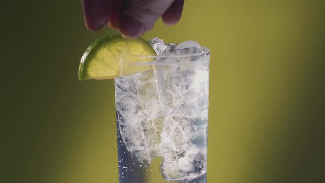 Lime added to a Soda water or a Sprite spinning glass, slow motion bubbles, ice cold.