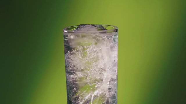 Soda water or a Sprite spinning glass, slow motion bubbles, ice cold.
