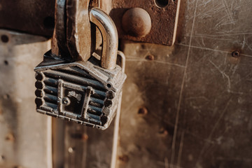 Padlock in the form of a hut hangs on the hinges of the closed gate. Metal gates.