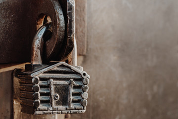 Padlock in the form of a hut hangs on the hinges of the closed gate. Metal gates.