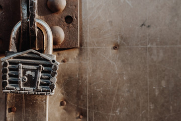 Padlock in the form of a hut hangs on the hinges of the closed gate. Metal gates.