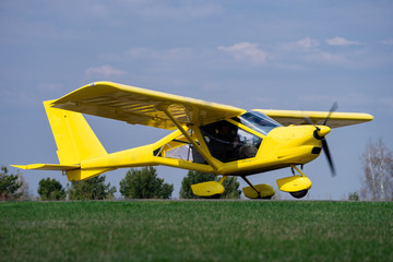 Fototapeta na wymiar small yellow charter airplane waiting on a green field to take off
