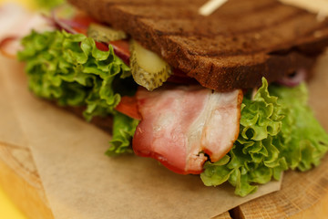 Closeup juicy sandwich with grilled dark bread and bacon