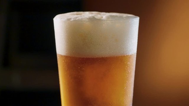 Pouring golden light beer into a rotating glass.