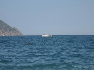 a white yacht is sailing in the sea not far from the mountain on a sunny day