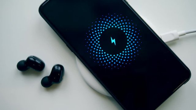 White surface with several gadgets recharging wirelessly. Wireless charging concept.