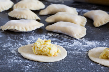 Knödel mit Kartoffeln und gebratenen Zwiebeln auf grauem hintergrund mit Mehl