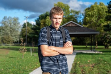 Angry student standing on a walkway that leads to a little pavilion.