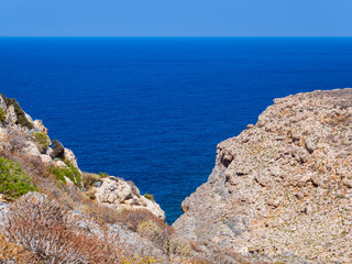 Fototapeta na wymiar Beautiful blue sea, rocky hills in the foreground