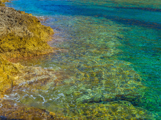 Extremely clear shallow water on small rocky beach in Crete, Greece