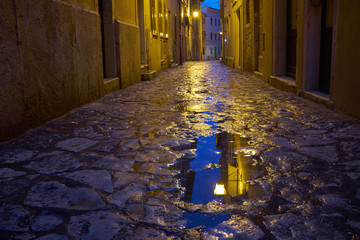 Rainy street of  Rovinj with lamp reflection in a puddle