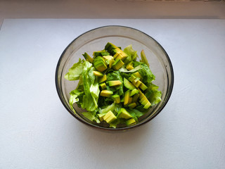 salad with avocado and sesame seeds, oil is poured, on a wooden. Avocado salad in a plate, vegetarian food, green dietary salad.