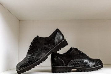 black patent leather shoes with a snake-skin pattern against a white shelf in the store