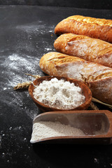 Assortment of baked bread and bread rolls on rustic black bakery table background