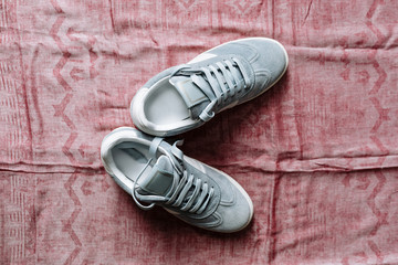 A pair of blue suede sneakers on a white sole with white accents on a pink background