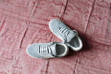 A pair of blue suede sneakers on a white sole with white accents on a pink background