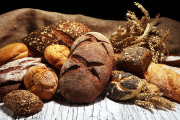 Assortment of baked bread and bread rolls on rustic white bakery table background