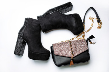 black suede ankle boots on a platform and thick heels with sparkles and a black bag with sparkles on the flap on a white background