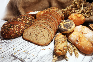 Assortment of baked bread and bread rolls on rustic white bakery table background