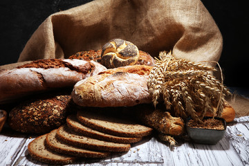 Assortment of baked bread and bread rolls on rustic white bakery table background