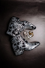 Fototapeta premium black thick-heeled ankle boots decorated with flowers embroidered with silver sequins and brooches on a gray paper background