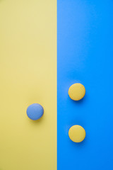 Sweet tasty blue and yellow french macaron cakes on yellow and blue background.