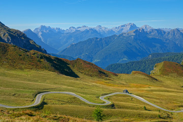 DRONE: Flying over the empty meadows and towards a winding asphalt road in Italy