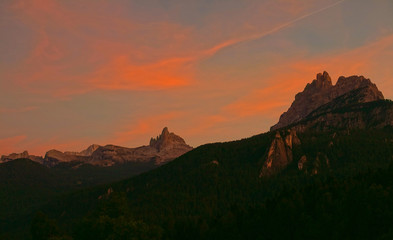 Fototapeta na wymiar AERIAL: Flying above the dense coniferous forest in the Dolomites at sunset.