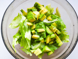 salad with avocado and sesame seeds, oil is poured, on a wooden. Avocado salad in a plate, vegetarian food, green dietary salad.