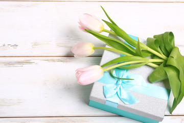 pink tulips on a gift box on a white wooden table