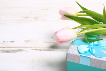 pink tulips on a gift box on a white wooden table