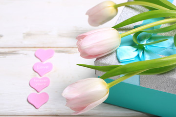 pink tulips on a gift box on a white wooden table