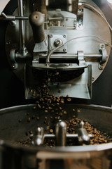 Fresh Roasted Natural Coffee Beans Cascading out of Industrial Coffee Bean Roaster Machine Inside the Coffee Shop