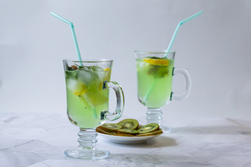 Refreshing lemonade from kiwi and lemon with ice on a light background. Horizontal orientation