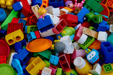 Top view on multicolored toy bricks and other used toys that fill the entire image. Perfect for backgrounds