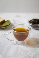 Green tea with jasmine in a transparent mug on a light background. Vertical orientation