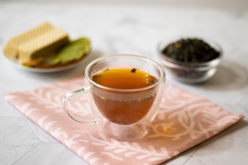 Green tea with jasmine in a transparent mug on a light background. Horizontal orientation