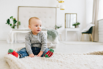 Naklejka premium Cute little toddler boy on a big blanket on the floor
