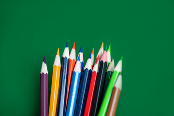 Colored pencil set on green background back to school and education concept / Crayons colorful