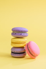 Tasty violet and yellow french macaron cakes on yellow background.