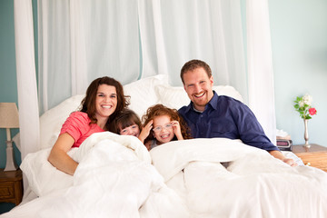 Fototapeta premium Happy Family Lying on Bed in Bedroom at Home