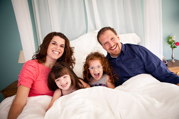Fototapeta premium Happy Family Lying on Bed in Bedroom at Home