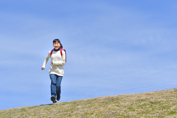 Fototapeta premium 青空で走る小学生の女の子（ランドセル）