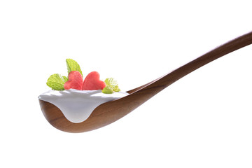 Plain yogurt on a spoon with fresh heart shape watermelon on top isolated on white background