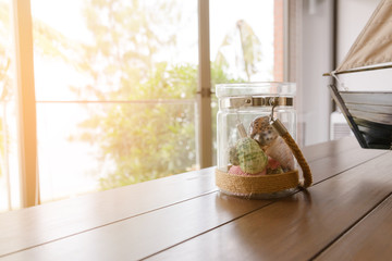 Variety of sea shells in glass jar on wooden table with copy space in living room. holiday concept
