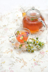 Healthy Herbal Flower fragrant  tea. Teapot and Tea cup with wild strawberry Flowers and leaves on table. Herbal Medicine, Phytotherapy Medicinal Herbs. spring or summer tea party. soft focus