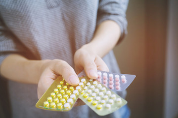 Obraz premium Close up young women hand contraceptive pill on with colorful pills strips. Contraception reduces childbirth and pregnant concept.