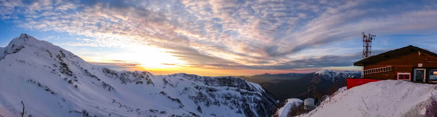 Watching sunset from Aibga mountain peak covered by snow. Gorki Gorod ski resort. Sochi, Russia.
