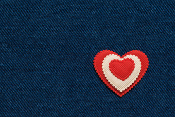 Naklejka na ściany i meble Red with white heart on uniform denim background.